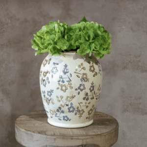 Decorative ceramic vase with leafy green lettuce on a rustic wooden surface.